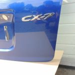 Mazda CX7 I MK1 aizmugurējā durvju apakšējā bagāžnieka vāka krāsa 34J Aurora Blue Mica
